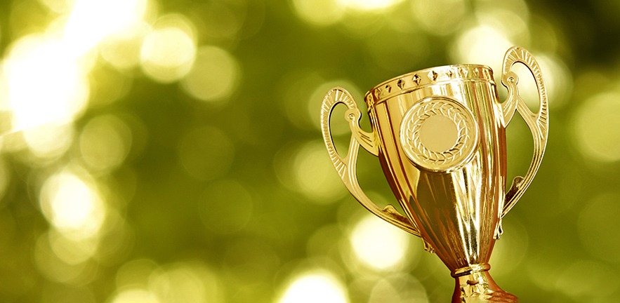 Gold trophy against a soft focus green nature background.