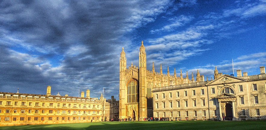 Sun shining on King's College, skies above full of scattered clouds.