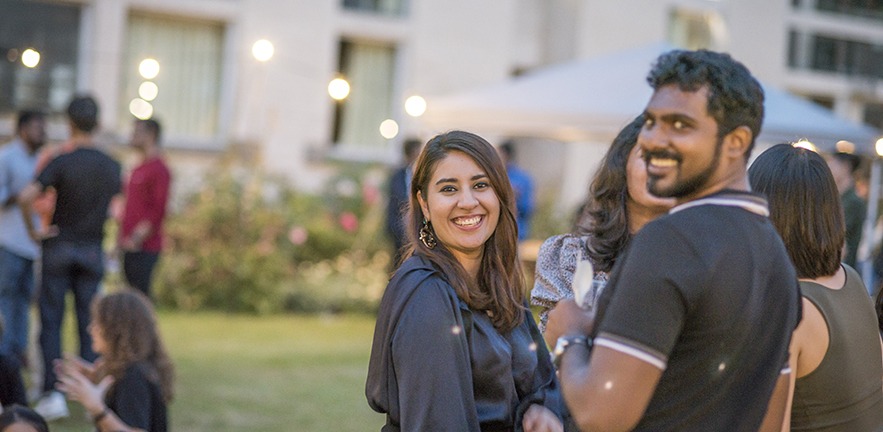 MBA students at a social in Cambridge, looking back towards the camera and smiling.