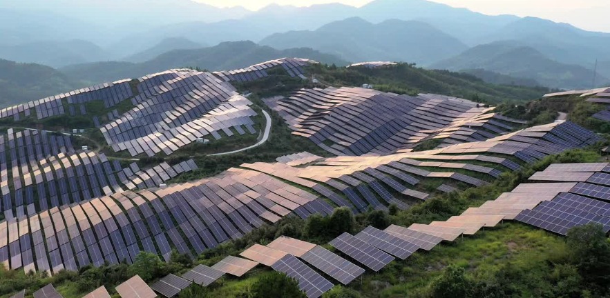 A bird's eye view of a mountain top solar farm in twilight.