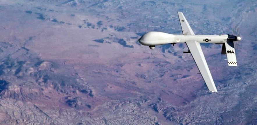 A predator drone flying high above a landscape.