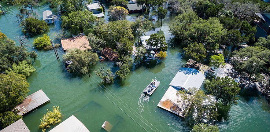 Aerial drone views high above flooding caused by climate change leaving entire neighborhood underwater and houses completely under water.