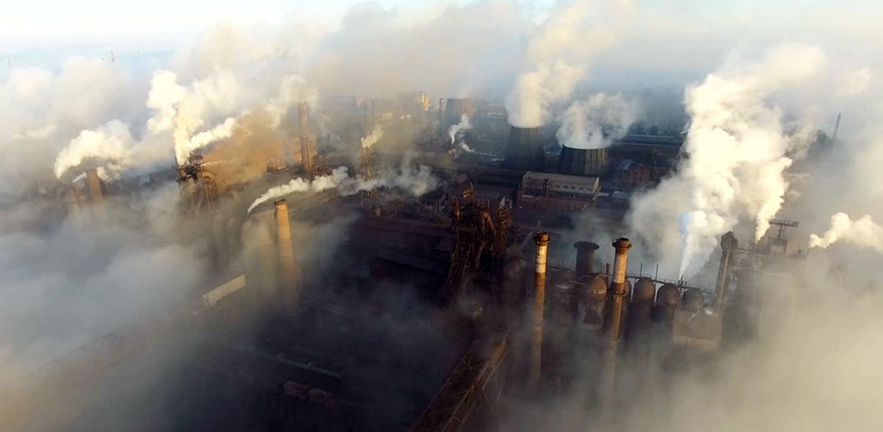 Plumes of smoke rise from industrial chimneys polluting the air.