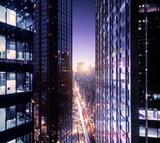 City view through skyscrapers at sunset, the city is still bright with light.