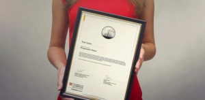 A delegate in a red dress holds up a framed Certificate of Achievement.