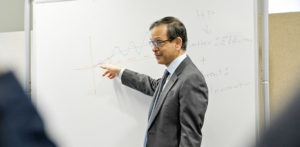 Professor Kishore Sengupta points out something on a whiteboard.