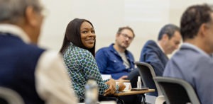 A smiling female Executive Education delegate looks over her shoulder at a fellow participant.