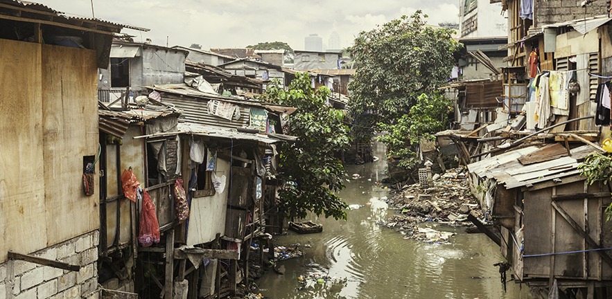 Shacks in a slum area along a small polluted canal.
