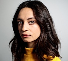 Close-up portrait of mid adult female staring at camera. Woman with sad expression on grey background.