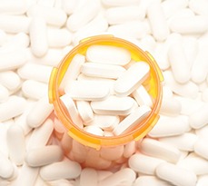 High angle view of a prescription bottled filled with pills surrounded by more of the same tablets.