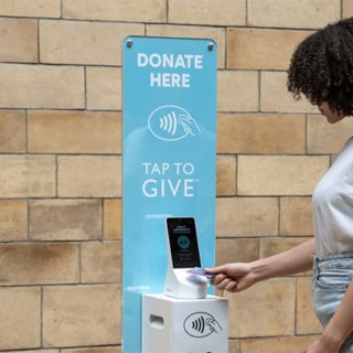 Woman using contactless device to donate money.