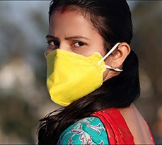 Young Indian women wearing pollution mask against Coronavirus or COVID-19 and standing on rooftop at home in Delhi, India.