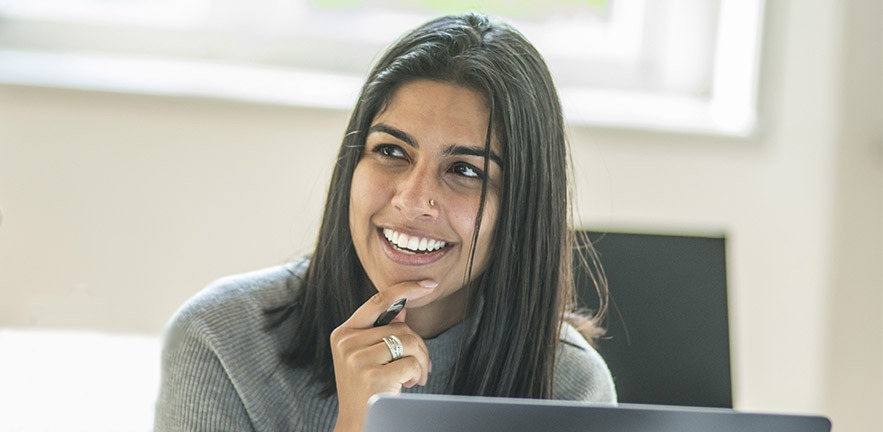 Smiling female MBA student on laptop.