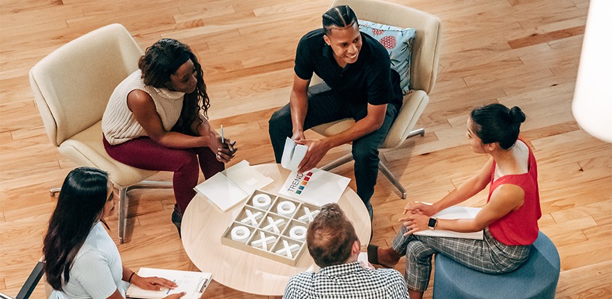 Five people sat around a table, having discussion.