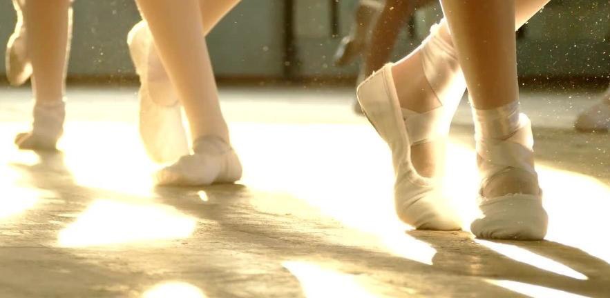 Close up of three ballerina's feet in ballet shoes.