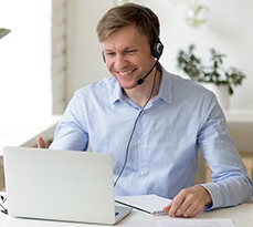 White man on a laptop and wearing headphones on a video call.