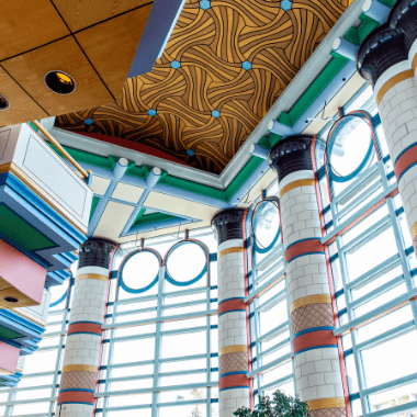 Inside Cambridge Judge Business School looking up at the patterned ceiling and the magnificent windows.
