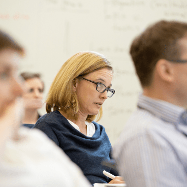 A delegate in a workshop listening and taking notes.