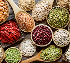 Collection of dry organic colorful cereal and grain seeds in wooden bowl in dark tone, consisted of bean, flax seed, goji berry, rice, peanut, job's tear, mung, and corn.