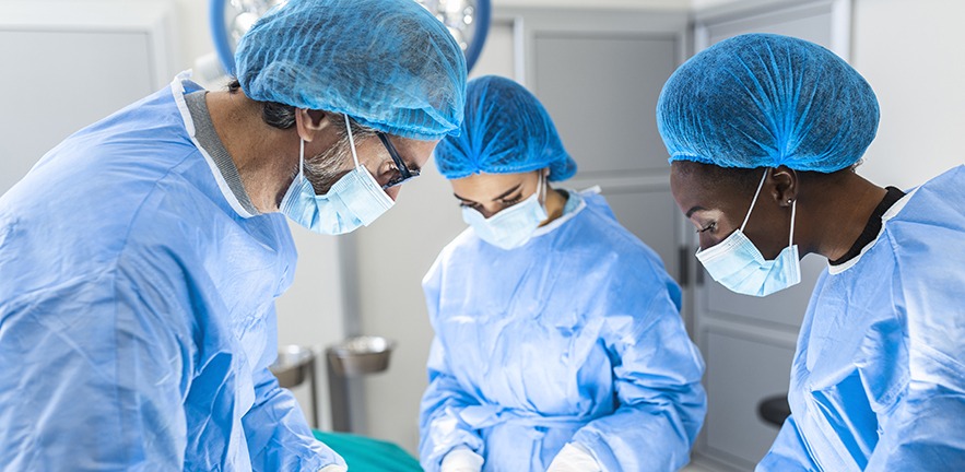 Group of surgeons doing surgery in hospital operating theatre.