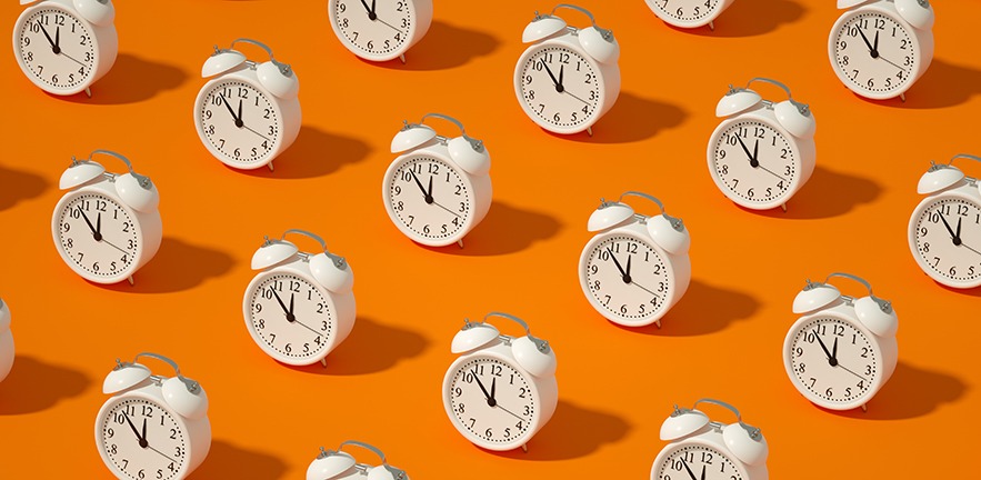 Illustration of multiple alarm clocks on a bright orange background.