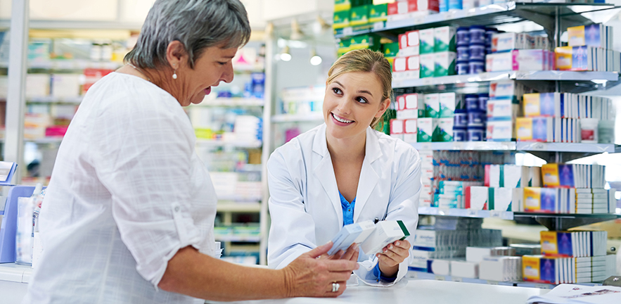 A young pharmacist assists a customer.