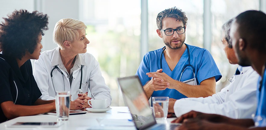 A group of five doctors, three men and two women, discussing treatment.