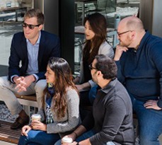Group of five MBA students sat outside on benches.