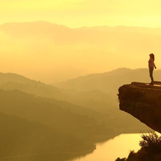 Woman breathing at the top of a cliff at sunrise in the mountains.