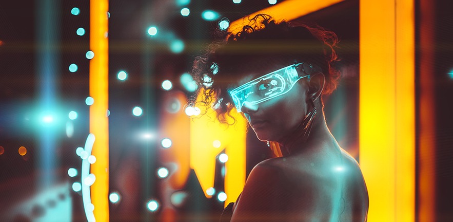 Neon light falls on a young woman in glowing glasses.