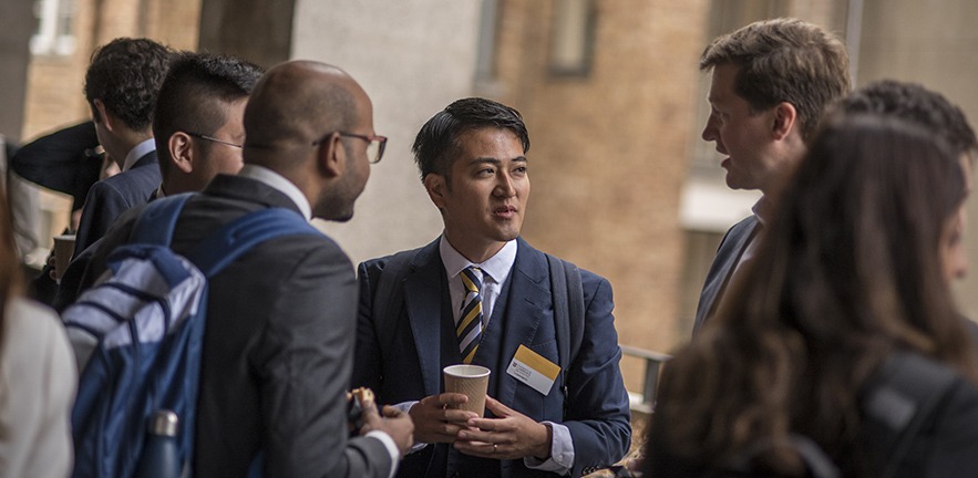 Group of male MBA students in suits talking.
