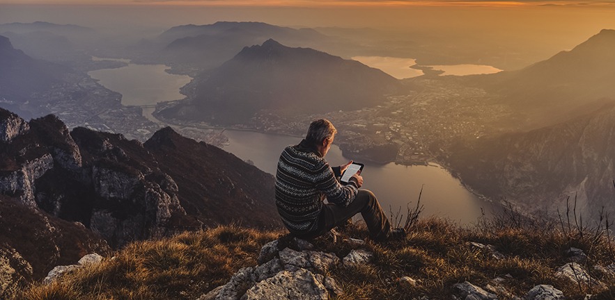 Hiker reading an e-book on a mountain during the golden hour.