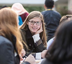 Group of MBA students outside, focus on a female white student with long hair.