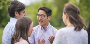 Group of four MBA students outside talking.