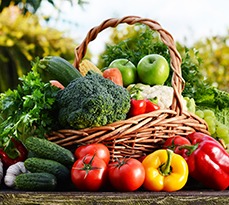 Wicker basket containing a range of organic vegetables from the garden.