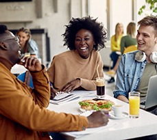 Group of happy students talking while studying at university cafeteria.