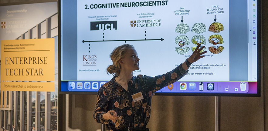 Woman giving a lecture in front of a PowerPoint presentation on neuroscience.