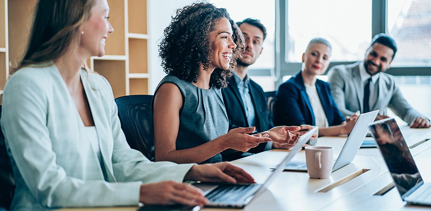 Group of smiling businesspeople in a morning meeting.