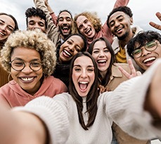 Multiracial friends taking big group selfie shot smiling at camera.