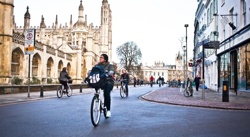 People cycling in front of the Kings College at Cambridge.