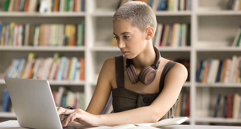 Focused student writing an essay on her laptop.