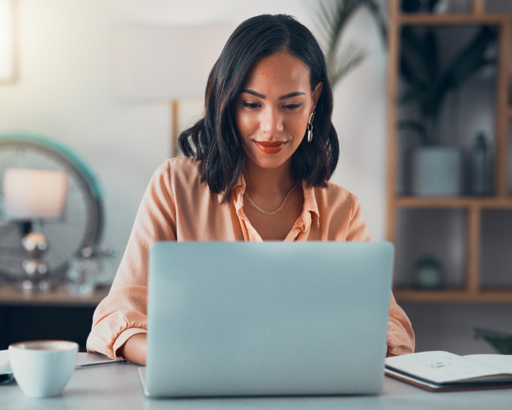 Girl smiling and focused in front of her laptop.