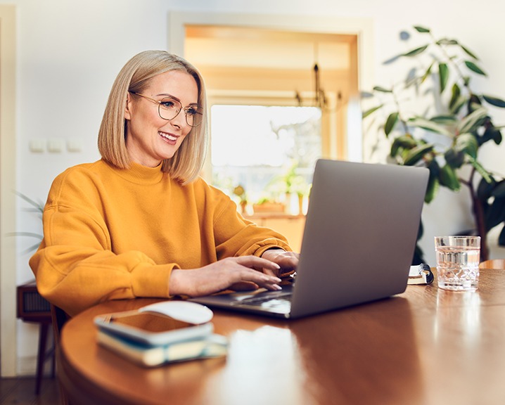 Smiling girl with glasses in front of her laptop.