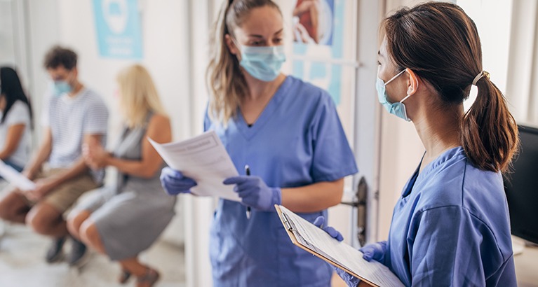 Nurses in discussion in patient waiting room.