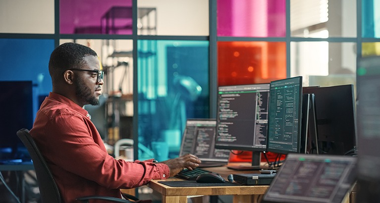 Man entering lines of code in a cool office.