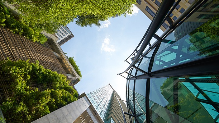 High rise glass buildings with green foliage growing on them.