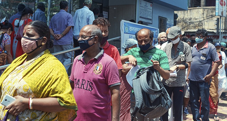 People waiting in long queues outside a Kolkata Corporation-run community health clinic for the COVID-19 vaccine.