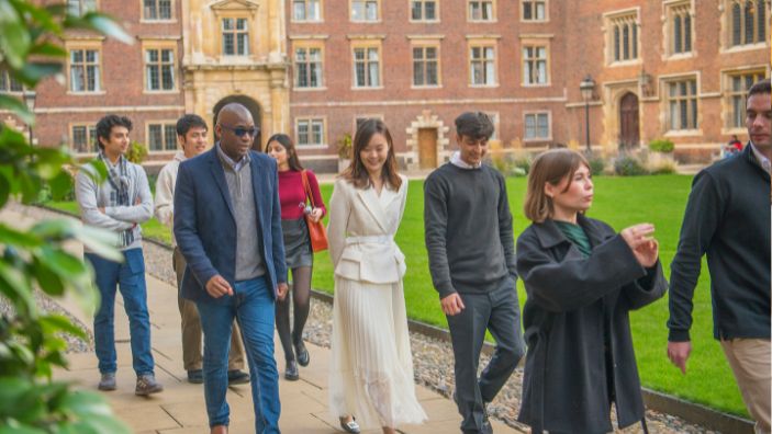 A group of MFin students walking through a Cambridge College talking to each other.