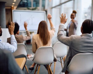People in a room raising their hands to vote.