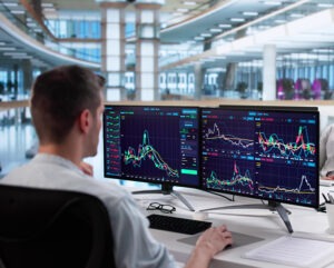 Man sitting at his desk looking at graphs and data on a computer.
